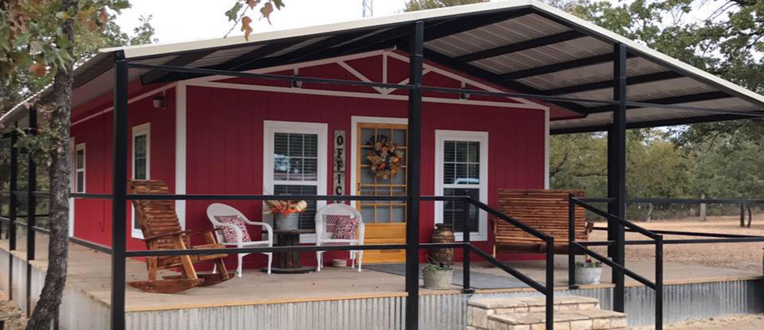 The office at Hog Mountain RV Ranch — a red building with a covered porch and rocking chairs